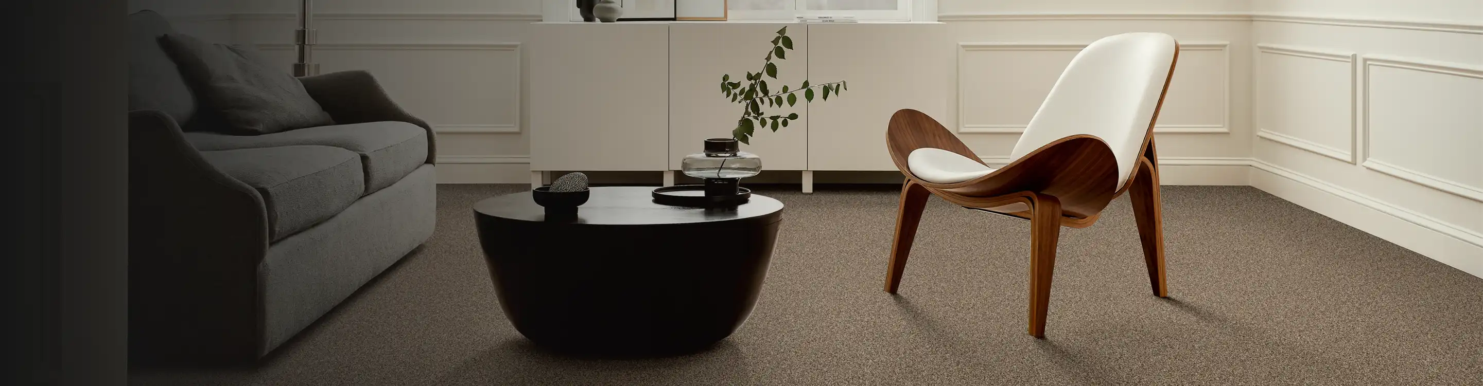 beige carpet in contemporary living room with modern chair, art and black coffee table